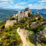 Photo d'une ruine de château avec un paysage montagneux et vert en fond.