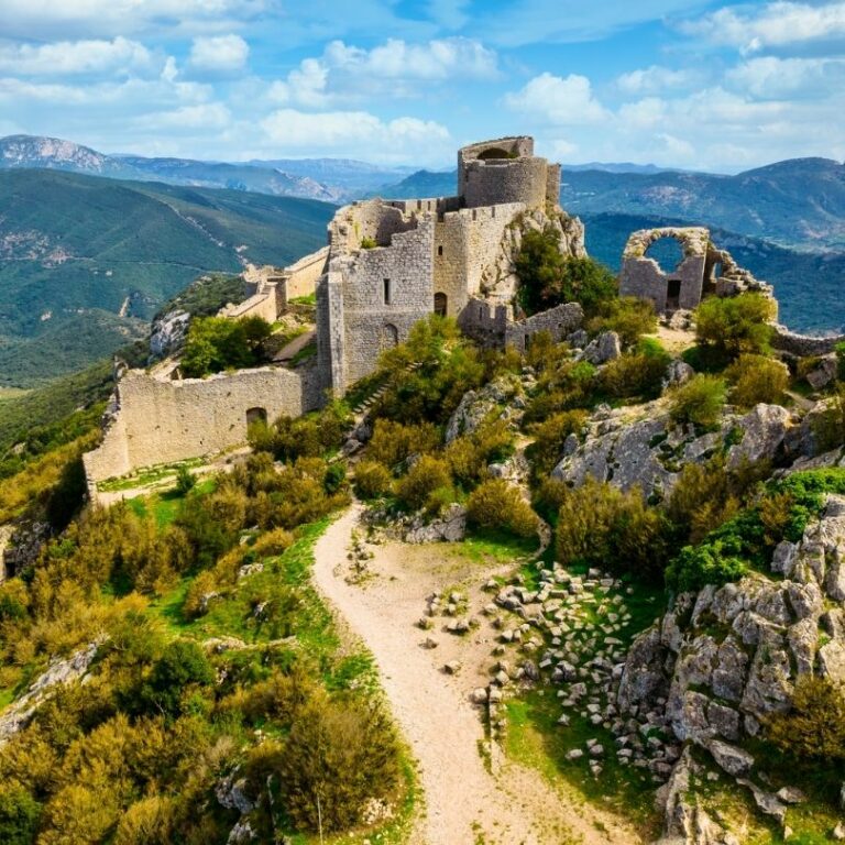 Photo d'une ruine de château avec un paysage montagneux et vert en fond.